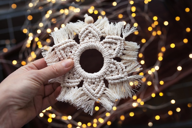 Décor de Noël en macramé. Flocon de neige de Noël sur fond marron foncé