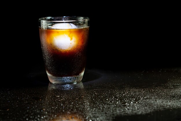 Décoration américaine froide avec boule de glace en verre de whisky sur une table noire.