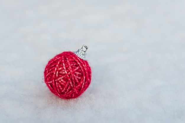 Décoration d'arbre de Noël faite de boule de fil rouge sur la neige naturelle