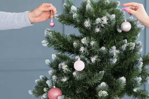 Décoration d'arbre de Noël. traditions de vacances en famille. mains accrochant des ornements de boule élégants à une épicéa verte.