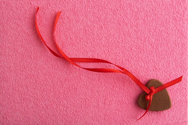 Décoration de biscuits au gingembre de la Saint-Valentin avec ruban rouge sur fond rose.