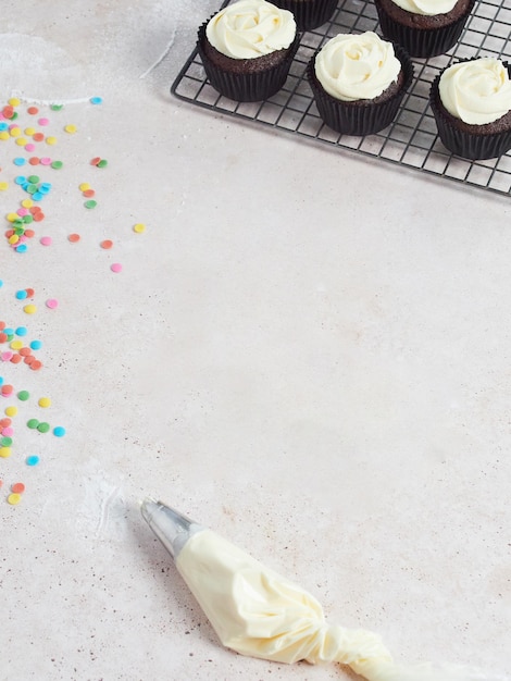 Décoration de boulangerie maison Comptoir avec poche à douille à la crème au beurre confettis comestibles colorés et cupcakes au chocolat Vue de dessus avec espace pour le texte