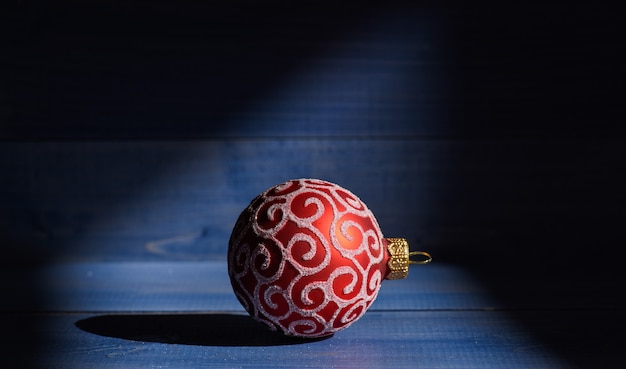 Décoration de boule de Noël dans l'ombre sur fond de bois vintage. Décorez le sapin de Noël avec des jouets traditionnels. Symbole du nouvel an et des vacances de Noël. Fêter Noël. Concept de vacances d'hiver.