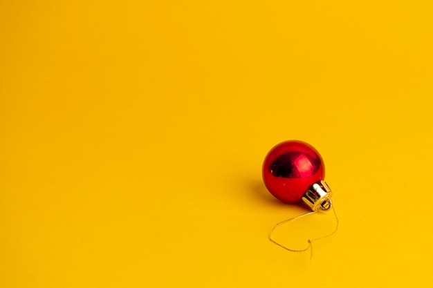 Décoration boule rouge d'un arbre de Noël sur fond jaune.