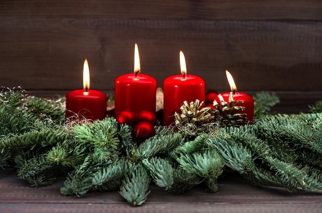 Décoration festive de l'avent avec quatre branches d'arbres de noël bougies rouges