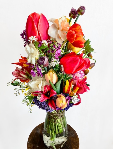 Photo la décoration intérieure et l'art d'arranger les bouquets bouquet de fleurs de jardin colorées sur fond blanc la composition comprend des tulipes jonquilles alliums muscari lunaria fritillaria et hellebore