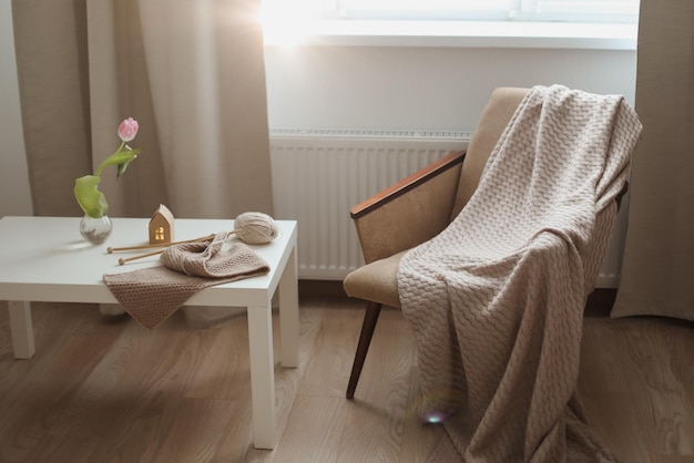 Décoration intérieure confortable avec une table à carreaux de chaise et des aiguilles à tricoter avec des fils de fil beige