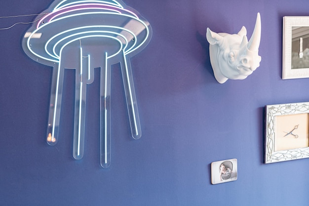 Décoration avec led et tête de rhinocéros blanc accrochée à un mur parmi des photos dans un salon de coiffure