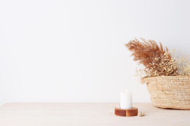 Décoration de la maison avec un panier de bougies et des fleurs sur le mur blanc Concept de conception d'intérieur Espace de copie en gros plan