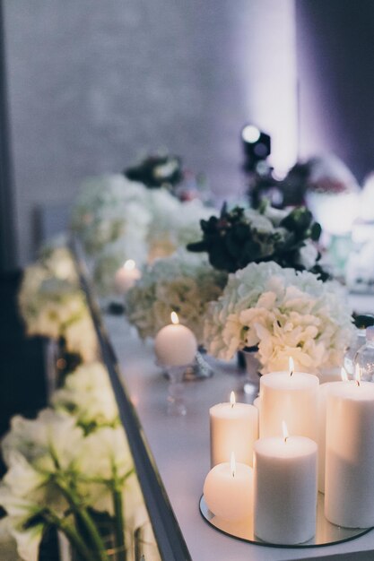 Décoration moderne lors d'une réception de mariage en soirée au restaurant Hortensia blanc élégant et bougies blanches modernes avec éclairage aux tables Restauration de luxe