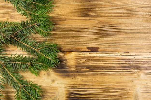 Décoration de Noël avec des branches de sapin sur fond de bois. Brindilles d'épinette sur table en bois. Vue de dessus, espace de copie