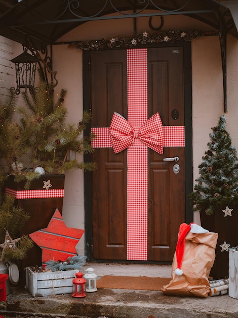 Photo décoration de noël du porche de la maison la porte d'entrée est ornée d'un grand noeud rouge