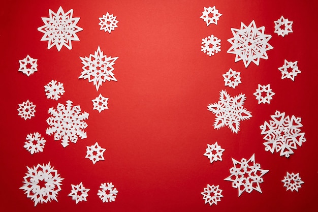 Décoration de Noël avec des flocons de neige blancs sur fond rouge à plat