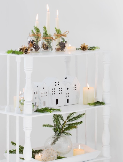 Décoration de Noël à la maison avec des bougies allumées dans un intérieur blanc