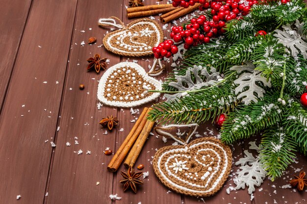 Décoration de Noël. Sapin du Nouvel An, feuilles fraîches, coeurs de biscuits au gingembre au crochet, épices et neige artificielle.