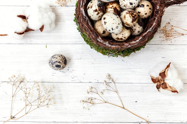 Décoration de Pâques avec oeuf en nid et coton sur table en bois blanc