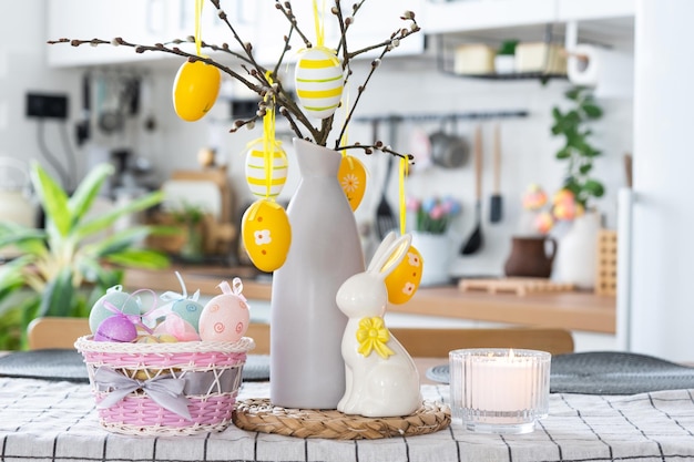 Décoration de Pâques d'oeufs colorés dans un panier et un lapin sur la table de la cuisine dans un style rustique Intérieur festif d'une maison de campagne