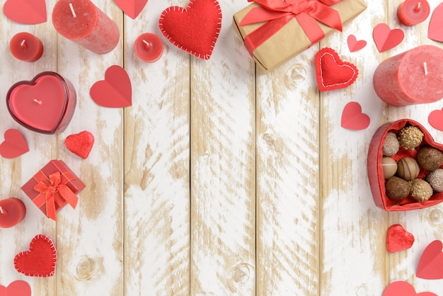 Photo décoration romantique saint valentin avec coeurs et bougies sur une table en bois blanc. vue de dessus, espace copie.