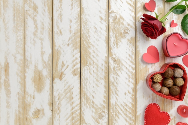 Photo décoration romantique saint valentin avec des roses et du chocolat sur un fond de table en bois blanc