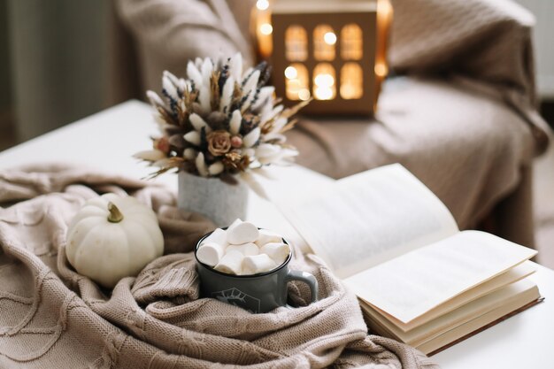 Photo décoration saisonnière d'automne à la maison avec une tasse de café et des fleurs séchées et une citrouille blanche et un livre