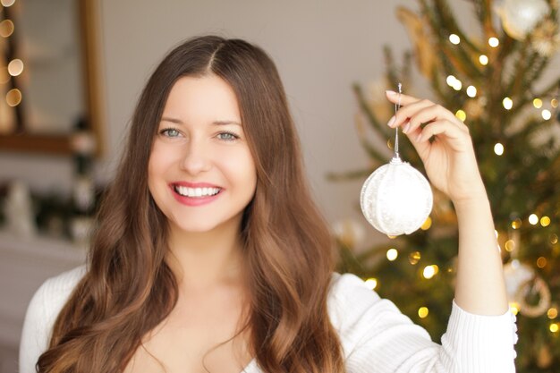 Décoration de sapin de Noël et concept de vacances d'hiver femme souriante heureuse tenant un ornement festif un...