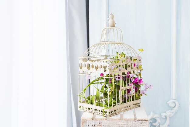 Décoration shabby chic avec une belle cage à oiseaux vintage et des fleurs