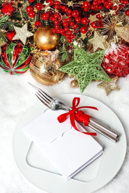 Décoration de table de fête avec boules, guirlandes dorées, bougie, arbre de Noël et baies rouges. concept d'invitation à dîner avec place pour votre texte