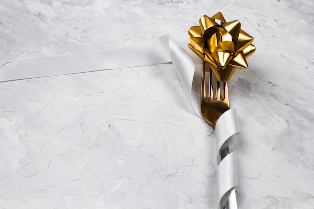 décoration de table pour un dîner, fourchette en or avec ruban de satin blanc brillant