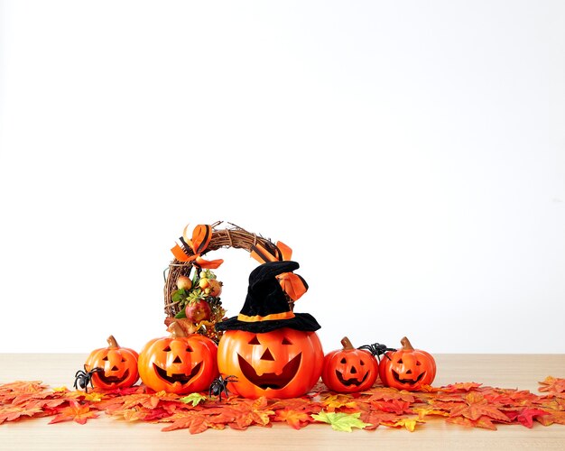 Décoration de vacances d'Halloween avec lanterne jack tête citrouille et feuilles d'automne sur bois de table avec fond de mur blanc, concept d'arrière-plan halloween, espace de copie.