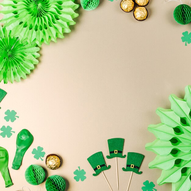 Décorations et accessoires pour la fête de la Saint-Patrick. Décorations en papier vert et or, chapeau, ballons, confettis, bonbons et symboles porte-bonheur sur fond blanc. Notion festive. Mise à plat, vue de dessus.