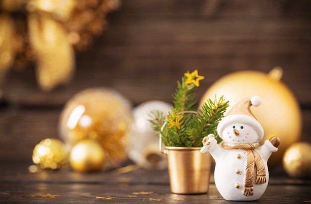 Décorations dorées de Noël et bonhomme de neige sur bois foncé