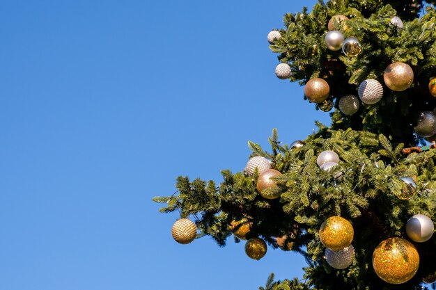 Décorations et guirlandes dorées et blanches du Nouvel An sur l'arbre de Noël à l'extérieur