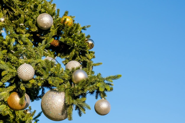 Décorations et guirlandes dorées et blanches du Nouvel An sur l'arbre de Noël à l'extérieur