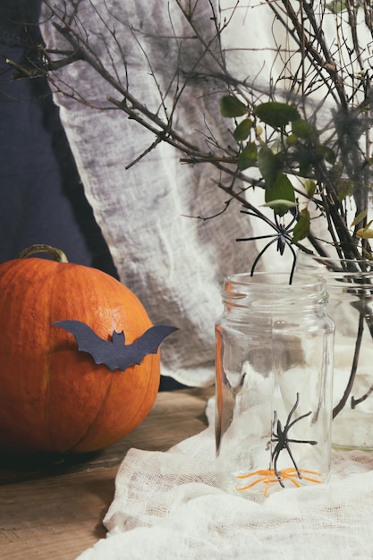 Décorations d'Halloween avec bougies, araignées, biscuits à la citrouille et pot pour friandises et baies noires, fond sombre, faible profondeur de champ, tonique