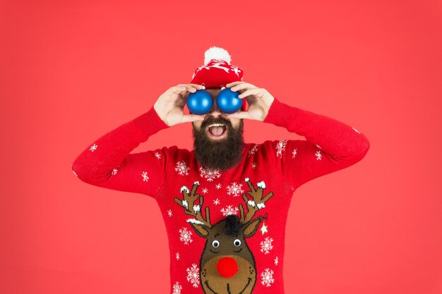 Photo décorations d'hiver nouvel an hipster gai barbu porter un pull d'hiver et un chapeau tenir des balles fête de noël vacances d'hiver évitez l'anxiété écrasante face aux facteurs de stress des vacances