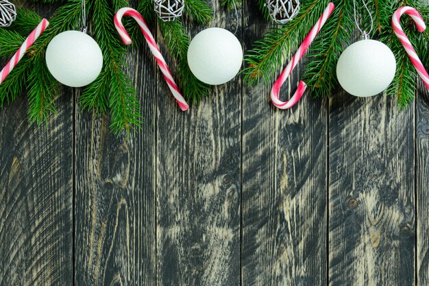 Décorations de Noël, boules blanches et canne en bonbon sur une table en bois grise. Vue de dessus, espace de copie.