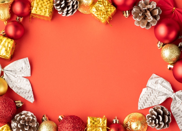 Décorations de Noël, boules, pomme de pin et arc sur fond rouge avec espace de copie.