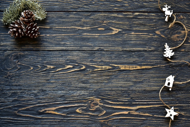 Photo décorations de noël, branche de cône et de sapin sur un fond en bois foncé. vue de dessus. contexte festif.