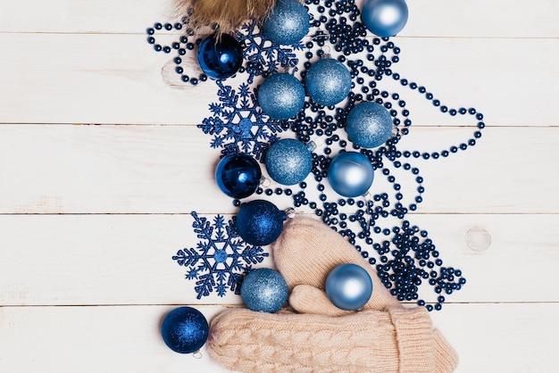 Décorations de Noël brillantes bleues, boules, étoiles et perles, café sur une table en bois avec un chapeau tricoté et des mitaines beiges, mise à plat, vue de dessus. Hiver confortable, nouvel an, concept de vacances.