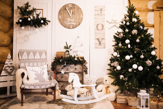 Décorations de Noël: chaise, arbre de Noël, commode, horloge, cadeaux sur le fond d'un mur en bois. Zone de photo de Noël. Zone photo de Noël avec un arbre de Noël.