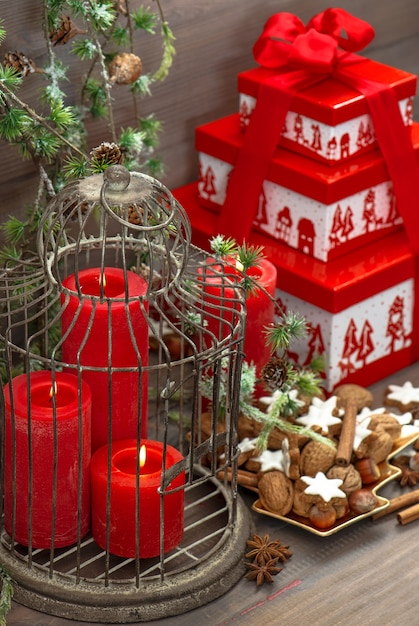 Décorations de Noël, coffret cadeau, bougies rouges, biscuits, noix et spieces sur fond en bois. maison de style vintage avec des branches de pin