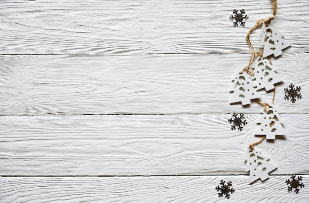 Décorations de Noël sur fond blanc en bois. Sapins en bois blanc sur une dentelle et des flocons de neige argentés. Fond d'hiver. Vue de dessus.