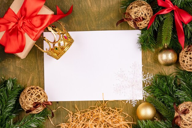 Décorations de Noël sur un fond texturé en bois vert, vue de dessus, espace libre pour la conception, feuille de papier blanc avec des crayons de couleur et une couronne