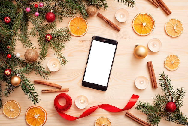 Décorations de Noël lumineuses sur la table avec téléphone mobile avec écran blanc vide