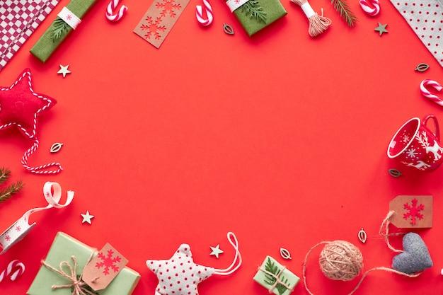 Décorations de Noël de nouvel an à la mode et zéro cadeau écologique. Mise à plat géométrique, vue de dessus sur papier rouge avec des étoiles en textile, des coffrets cadeaux et des cannes de bonbon. Cadre avec copie-espace.