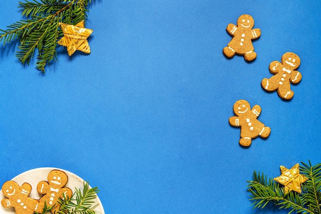 Décorations de Noël à plat avec des biscuits de bonhomme en pain d'épice, décor copie espace fond bleu