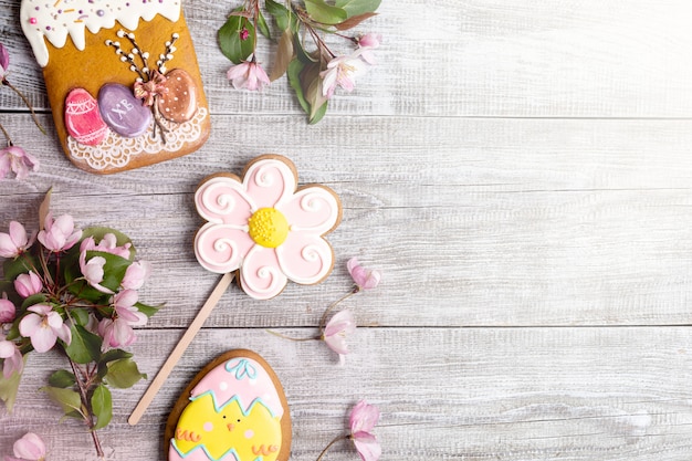 Décorations de Pâques disposées sur une table en bois. Branches de pommier rose, pains d'épice comme gâteau de Pâques, fleur et œuf.