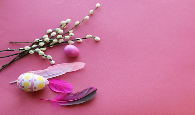 Décorations de Pâques oeufs plumes et brindilles de saule sur fond rose