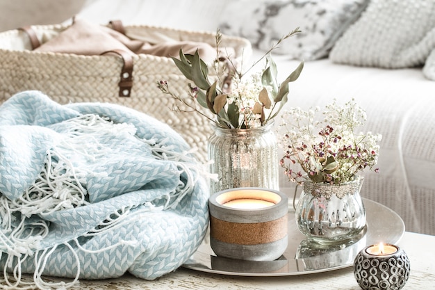 Décorations pour la maison à l'intérieur. Une couverture turquoise et un panier en osier avec un vase de fleurs et de bougies