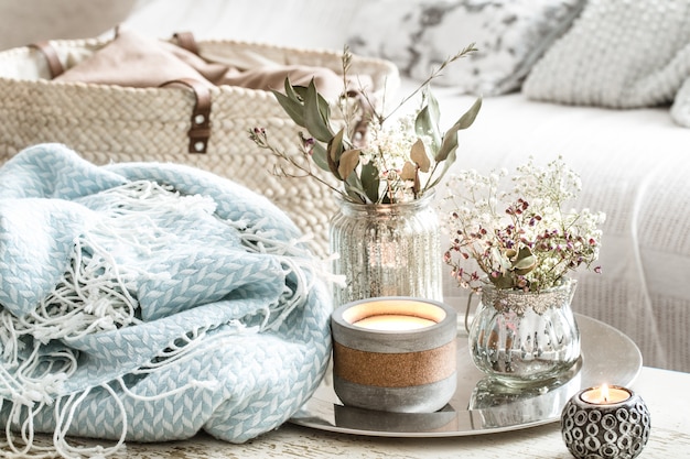 Décorations pour la maison à l'intérieur. Une couverture turquoise et un panier en osier avec un vase de fleurs et de bougies